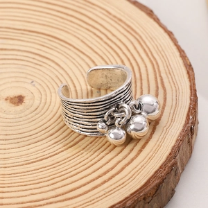Vintage textured silver ring with hanging bell charms on an organic wood base