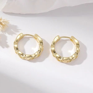 Polished golden twist hoop earrings with woven texture on a minimalist white backdrop