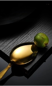 Macro shot of gold mirror-polished stainless steel spoon with clear lime reflection