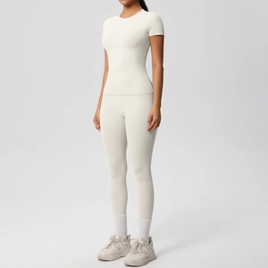 Detail view of cream short-sleeved slim-fit sports top and high-waisted yoga leggings