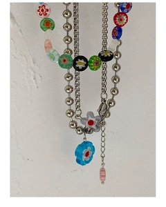 Détail d'un collier multicouche Y2K avec perles argentées et pendentifs fleurs colorés
