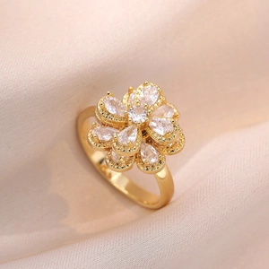Detailed view of rotating golden flower ring with sparkling zircon stones on soft fabric