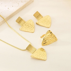 Detailed view of 18K gold plated geometric jewelry set with hammered texture on beige linen