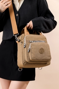 Détail du sac multifonction en nylon marron avec larges bandoulières tissées et zips en métal