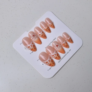 Detail of almond press-on nails with leopard print, 3D floral accents and red rhinestones