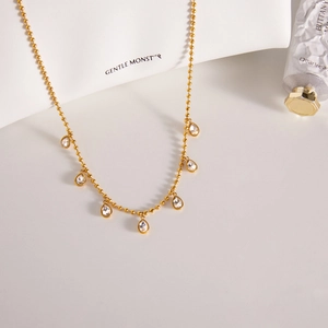 Detailed shot of golden bead chain necklace featuring seven sparkling water-drop crystals