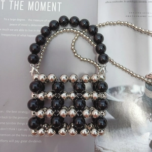 Detail of hand-woven mini beaded bag featuring metallic silver and black geometric grid