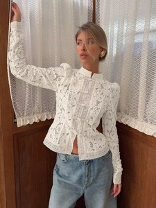 Détail de la blouse blanche en dentelle avec boutons chinois et col montant élégant