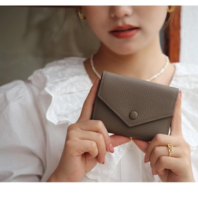 Close-up of elephant gray lychee leather card holder in model hands with V-flap design