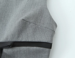 Detailed close-up of grey twill fabric and black satin ribbon bow on the waistline