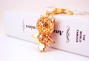 Detailed view of golden owl keychain with red rhinestones and intricate hollow metalwork