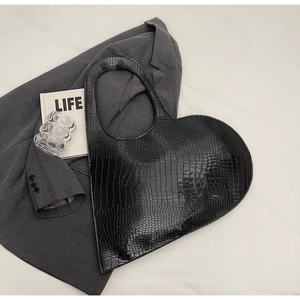 Detailed view of black heart-shaped handbag in crocodile pattern with glossy patent leather