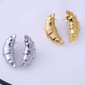 Detailed view of croissant-shaped stud earrings in polished gold and silver metal