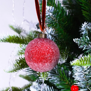 Frosted red Christmas ball ornament with velvet ribbon on a festive pine branch