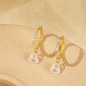 Close-up of gold heart-shaped zircon drop earrings with shimmering diamond inlay details