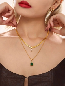 Detail of double-layer gold chain necklace with green emerald and zircon pendants