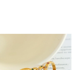 Detailed view of a gold-finish ring featuring multi-colored gemstones on a ceramic edge