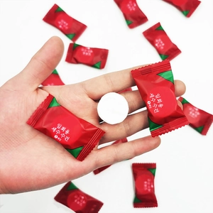 Portable disposable compressed facial towel in red candy-shaped packaging for travel use