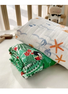 Close-up of bamboo cotton muslin baby blankets with ocean and jungle patterns