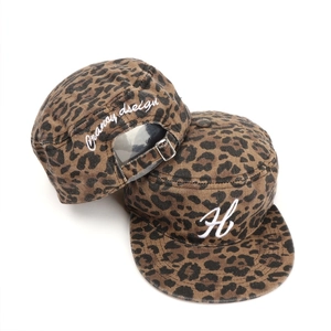 Dettaglio cappelli militari leopardati con ricamo bianco e fibbia in metallo