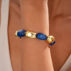 Detail of blue glitter acrylic and gold irregular oval beads on bohemian stretch bracelet