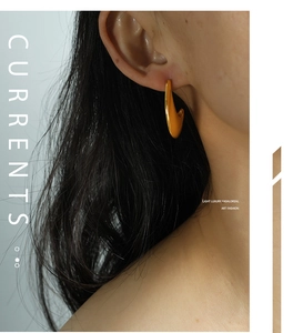Close-up of model wearing thick gold C-shaped earrings with a polished finish