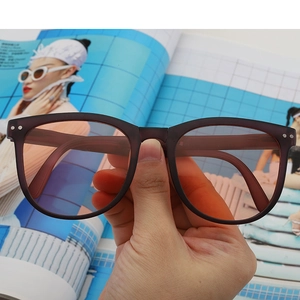 Detail of round sunglasses with orange tinted lenses held over a magazine background