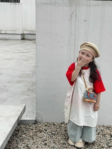 Mädchen in rotem T-Shirt mit bunter Baskenmütze und kleiner Denim-Umhängetasche in Schalenform