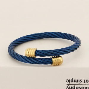 Close-up of blue cable wire bracelet with gold metal ends on a white book edge