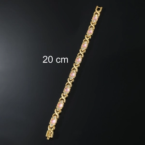 Macro view of a 20 cm gold magnetic energy bracelet with pink gems and crystal details