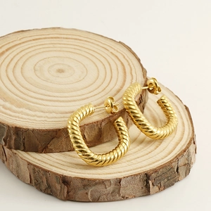 Créoles chic torsadées en acier inoxydable plaqué or 18 carats sur socle en bois
