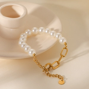 Detailed view of 18K gold stainless steel chain with pearls on white ceramic dish