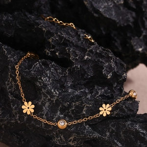 Detailed view of 18K gold plated flower bracelet with crystals on black mineral rock