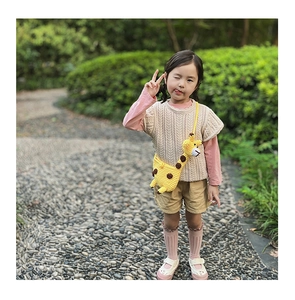 Detail of a handmade knit giraffe crossbody bag and beige crochet vest for toddler girls