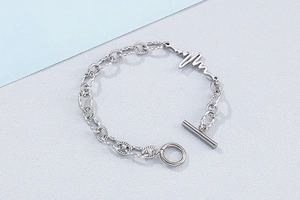 Detail view of silver lifeline charm bracelet with a toggle clasp on a minimal background