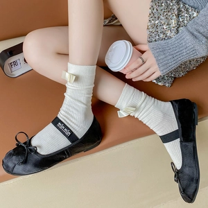 Detail of black suede Mary Jane shoes with bows and white mid-calf socks