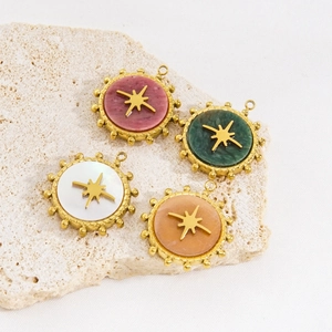 Stainless steel gold round pendants with colorful stones and star motifs on stone surface