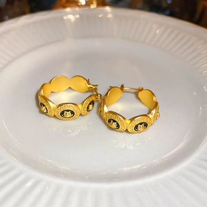 Vue détaillée de boucles d'oreilles vintage dorées avec émail noir et charmes de portrait