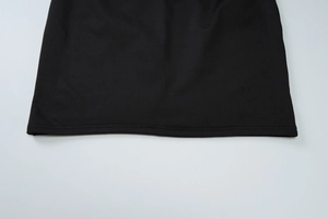 Detailed close-up showing high-quality stitching on the bottom edge of a black knit dress