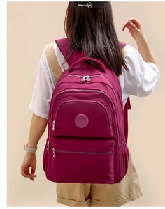 Rear view of model wearing a purple oxford nylon backpack with multiple zipper pockets