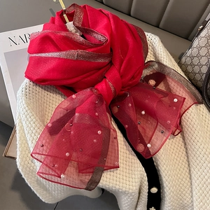 Detailed view of red silk-like scarf with pearl embellishments and gold glitter trim