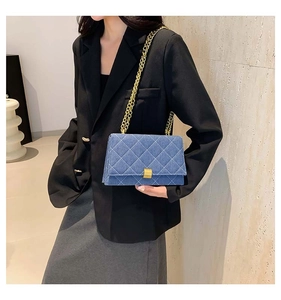 Close-up of blue denim crossbody bag with quilted pattern and gold chain strap detail