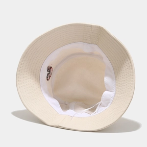 Détail du bob en coton blanc montrant la bande de transpiration et la broderie champignon