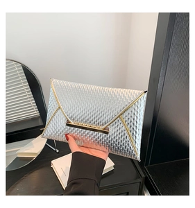 Dettaglio pochette a busta argento con trama a scaglie e chiusura metallica dorata