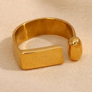 Close-up of geometric gold-plated stainless steel ring with rectangle and oval ends