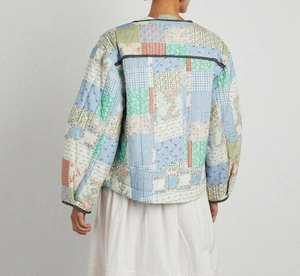 Detail of multi-color patchwork quilted jacket featuring floral and plaid stitching patterns