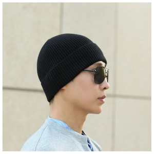 Profile view of a man wearing a black ribbed beanie and sunglasses outdoors