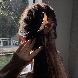 Close-up of a large amber hair claw clip worn by a model in soft natural window light