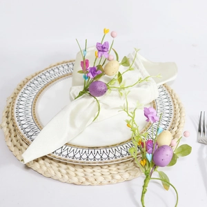 Detailed view of Easter napkin ring with purple faux eggs, silk flowers and green foliage