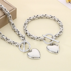 Silver stainless steel OT buckle chain necklace set with polished heart pendant on beige texture